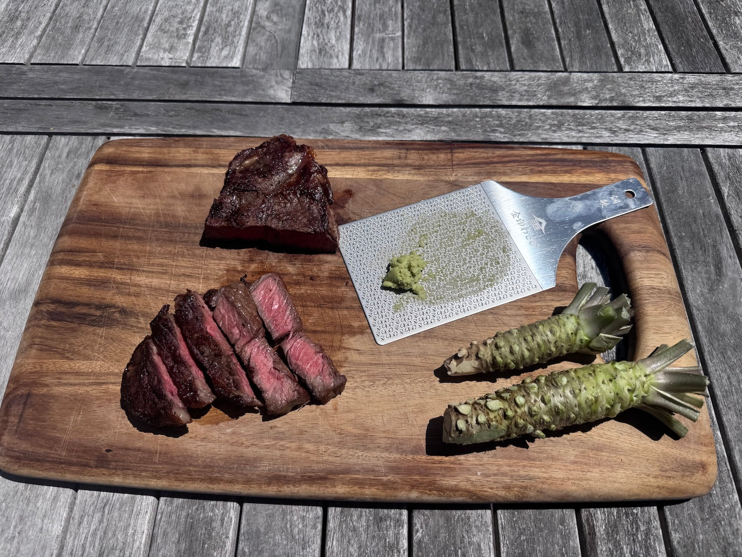 Grated real wasabi on a cutting board with one sliced NY strip steak